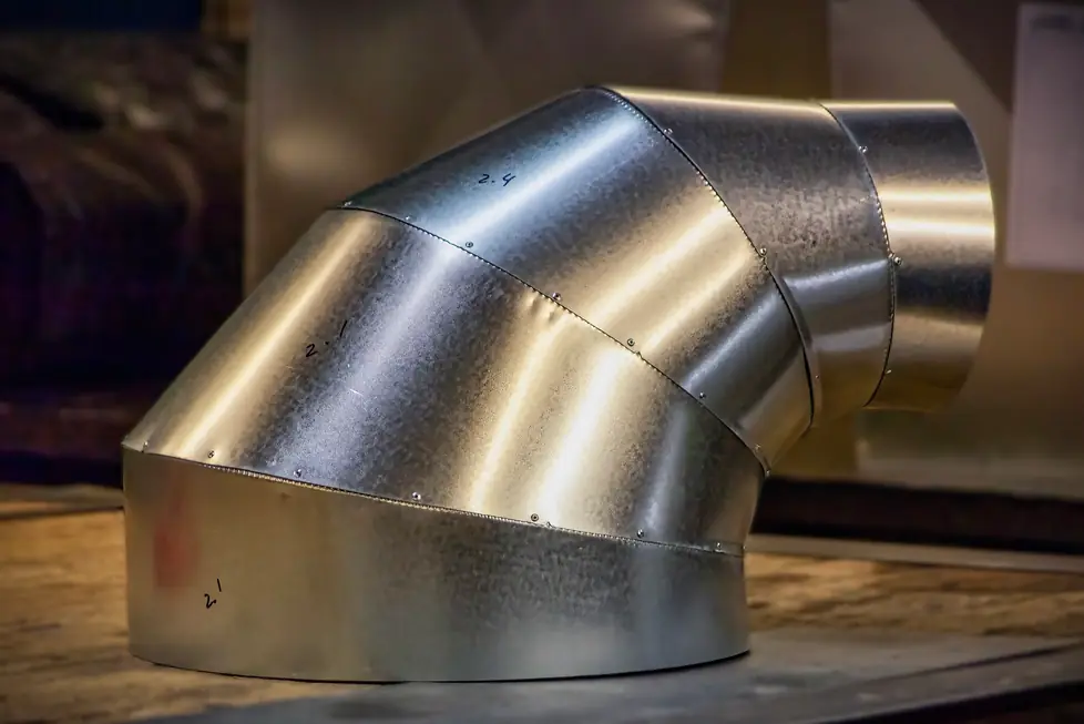 A gored galvanized elbow fitting built in the All Seasons sheet-metal shop